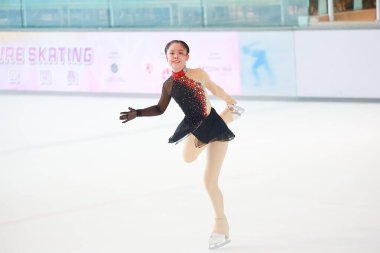 Mavi elbiseli yetenekli artistik patinajcı zarif bir şekilde karmaşık bir duruş sergiliyor.