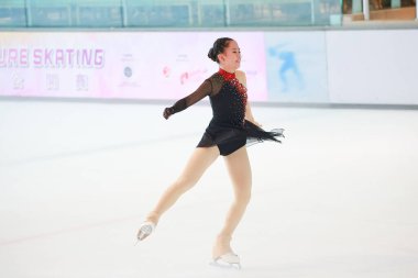 Mavi elbiseli yetenekli artistik patinajcı zarif bir şekilde karmaşık bir duruş sergiliyor.