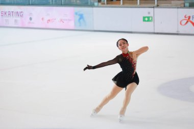 Mavi elbiseli yetenekli artistik patinajcı zarif bir şekilde karmaşık bir duruş sergiliyor.