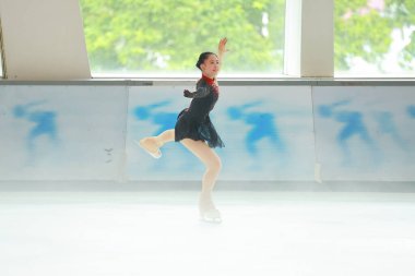 Mavi elbiseli yetenekli artistik patinajcı zarif bir şekilde karmaşık bir duruş sergiliyor.