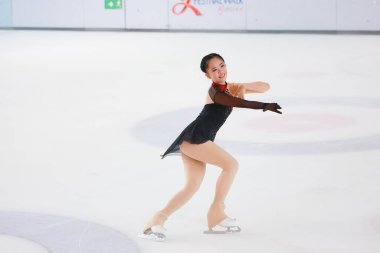 Mavi elbiseli yetenekli artistik patinajcı zarif bir şekilde karmaşık bir duruş sergiliyor.