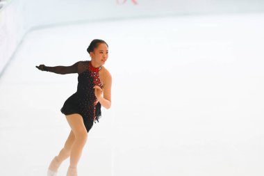 Mavi elbiseli yetenekli artistik patinajcı zarif bir şekilde karmaşık bir duruş sergiliyor.