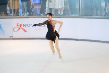 Mavi elbiseli yetenekli artistik patinajcı zarif bir şekilde karmaşık bir duruş sergiliyor.