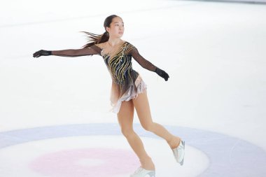 Mavi elbiseli yetenekli artistik patinajcı zarif bir şekilde karmaşık bir duruş sergiliyor.