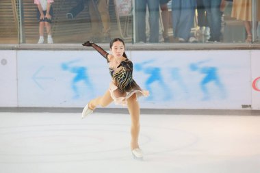 Mavi elbiseli yetenekli artistik patinajcı zarif bir şekilde karmaşık bir duruş sergiliyor.