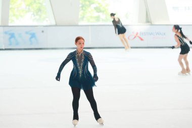 Mavi elbiseli yetenekli artistik patinajcı zarif bir şekilde karmaşık bir duruş sergiliyor.