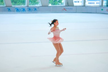 Mavi elbiseli yetenekli artistik patinajcı zarif bir şekilde karmaşık bir duruş sergiliyor.