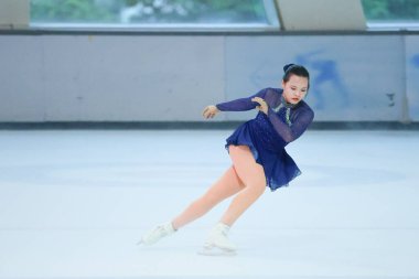 Mavi elbiseli yetenekli artistik patinajcı zarif bir şekilde karmaşık bir duruş sergiliyor.