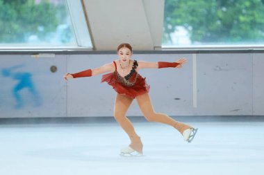 Mavi elbiseli yetenekli artistik patinajcı zarif bir şekilde karmaşık bir duruş sergiliyor.