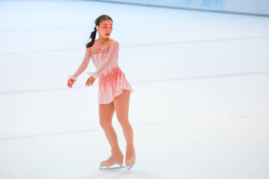 Mavi elbiseli yetenekli artistik patinajcı zarif bir şekilde karmaşık bir duruş sergiliyor.