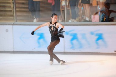 Mavi elbiseli yetenekli artistik patinajcı zarif bir şekilde karmaşık bir duruş sergiliyor.