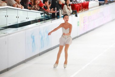 Mavi elbiseli yetenekli artistik patinajcı zarif bir şekilde karmaşık bir duruş sergiliyor.