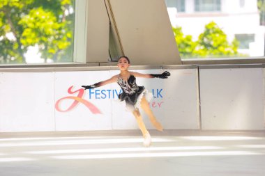 Mavi elbiseli yetenekli artistik patinajcı zarif bir şekilde karmaşık bir duruş sergiliyor.