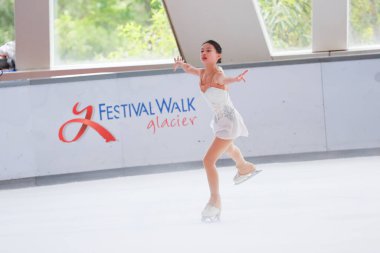 Mavi elbiseli yetenekli artistik patinajcı zarif bir şekilde karmaşık bir duruş sergiliyor.