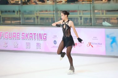 Mavi elbiseli yetenekli artistik patinajcı zarif bir şekilde karmaşık bir duruş sergiliyor.