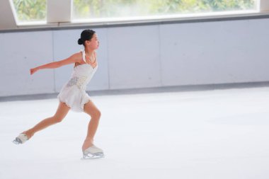 Mavi elbiseli yetenekli artistik patinajcı zarif bir şekilde karmaşık bir duruş sergiliyor.