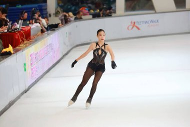 Mavi elbiseli yetenekli artistik patinajcı zarif bir şekilde karmaşık bir duruş sergiliyor.