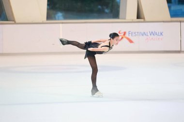 Mavi elbiseli yetenekli artistik patinajcı zarif bir şekilde karmaşık bir duruş sergiliyor.