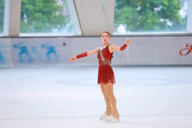 Mavi elbiseli yetenekli artistik patinajcı zarif bir şekilde karmaşık bir duruş sergiliyor.