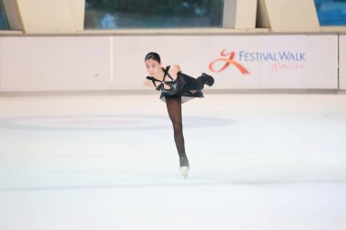 Mavi elbiseli yetenekli artistik patinajcı zarif bir şekilde karmaşık bir duruş sergiliyor.