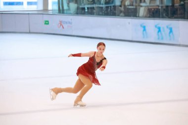 Mavi elbiseli yetenekli artistik patinajcı zarif bir şekilde karmaşık bir duruş sergiliyor.