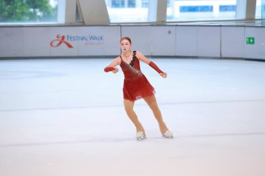 Mavi elbiseli yetenekli artistik patinajcı zarif bir şekilde karmaşık bir duruş sergiliyor.