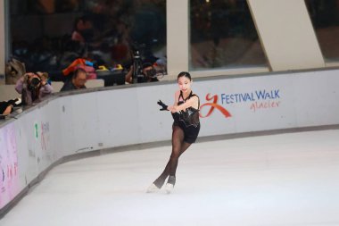 Mavi elbiseli yetenekli artistik patinajcı zarif bir şekilde karmaşık bir duruş sergiliyor.