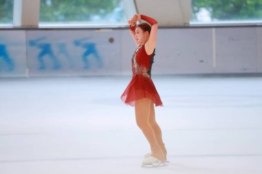 Mavi elbiseli yetenekli artistik patinajcı zarif bir şekilde karmaşık bir duruş sergiliyor.