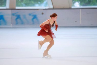 Mavi elbiseli yetenekli artistik patinajcı zarif bir şekilde karmaşık bir duruş sergiliyor.