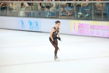 Mavi elbiseli yetenekli artistik patinajcı zarif bir şekilde karmaşık bir duruş sergiliyor.