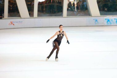 Mavi elbiseli yetenekli artistik patinajcı zarif bir şekilde karmaşık bir duruş sergiliyor.