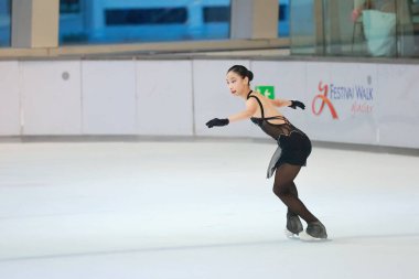 Mavi elbiseli yetenekli artistik patinajcı zarif bir şekilde karmaşık bir duruş sergiliyor.