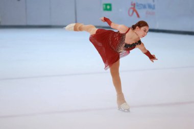 Mavi elbiseli yetenekli artistik patinajcı zarif bir şekilde karmaşık bir duruş sergiliyor.