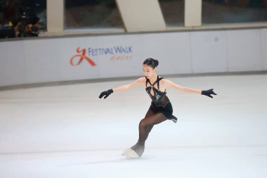 Mavi elbiseli yetenekli artistik patinajcı zarif bir şekilde karmaşık bir duruş sergiliyor.