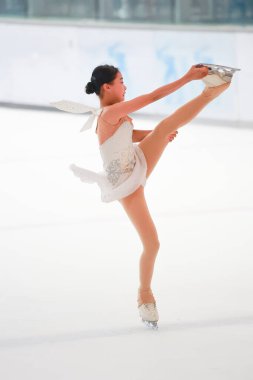 Mavi elbiseli yetenekli artistik patinajcı zarif bir şekilde karmaşık bir duruş sergiliyor.