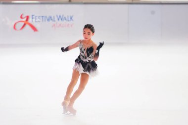 Mavi elbiseli yetenekli artistik patinajcı zarif bir şekilde karmaşık bir duruş sergiliyor.