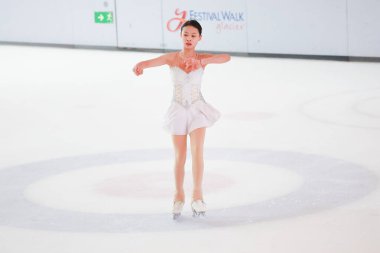 Mavi elbiseli yetenekli artistik patinajcı zarif bir şekilde karmaşık bir duruş sergiliyor.