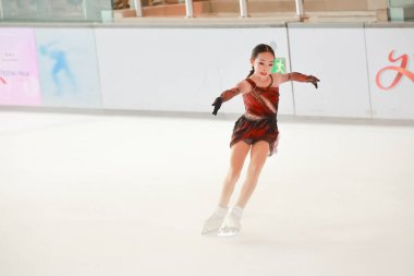 Mavi elbiseli yetenekli artistik patinajcı zarif bir şekilde karmaşık bir duruş sergiliyor.