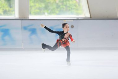 Mavi elbiseli yetenekli artistik patinajcı zarif bir şekilde karmaşık bir duruş sergiliyor.