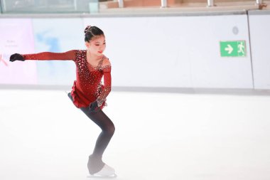 Mavi elbiseli yetenekli artistik patinajcı zarif bir şekilde karmaşık bir duruş sergiliyor.