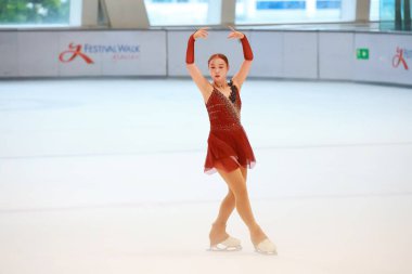 Mavi elbiseli yetenekli artistik patinajcı zarif bir şekilde karmaşık bir duruş sergiliyor.