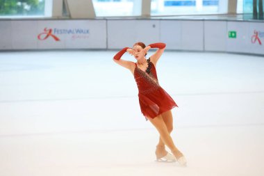 Mavi elbiseli yetenekli artistik patinajcı zarif bir şekilde karmaşık bir duruş sergiliyor.