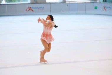 Mavi elbiseli yetenekli artistik patinajcı zarif bir şekilde karmaşık bir duruş sergiliyor.