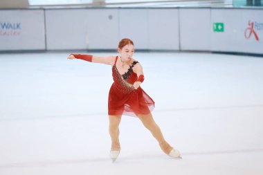 Mavi elbiseli yetenekli artistik patinajcı zarif bir şekilde karmaşık bir duruş sergiliyor.