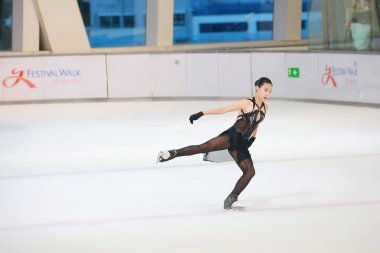 Mavi elbiseli yetenekli artistik patinajcı zarif bir şekilde karmaşık bir duruş sergiliyor.