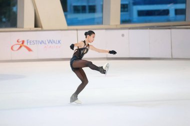 Mavi elbiseli yetenekli artistik patinajcı zarif bir şekilde karmaşık bir duruş sergiliyor.