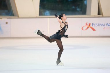 Mavi elbiseli yetenekli artistik patinajcı zarif bir şekilde karmaşık bir duruş sergiliyor.