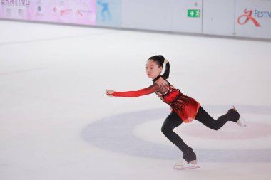 Mavi elbiseli yetenekli artistik patinajcı zarif bir şekilde karmaşık bir duruş sergiliyor.