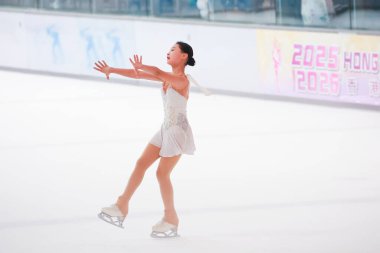 Mavi elbiseli yetenekli artistik patinajcı zarif bir şekilde karmaşık bir duruş sergiliyor.