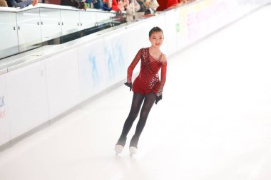 Mavi elbiseli yetenekli artistik patinajcı zarif bir şekilde karmaşık bir duruş sergiliyor.